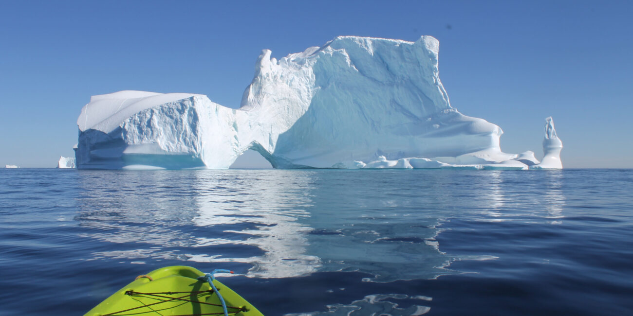 Photo of Karolina Bochenek kayaking in East Greenland next to ice berg